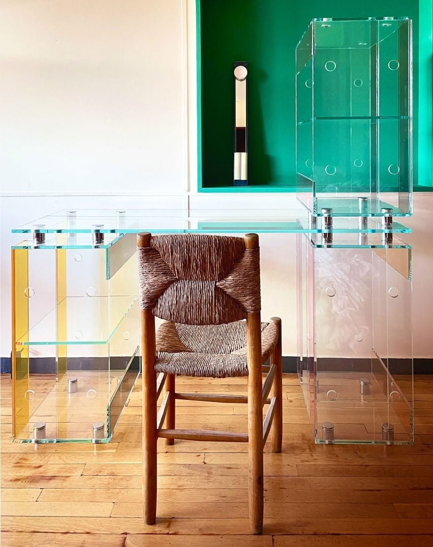 A clear plastic desk composed of stacked glass boxes designed by Marie & Alexandre, emphasizing their craft and design approach.