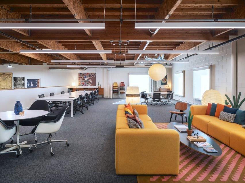 An orange couch that adds a pop of color in the renovated office space.