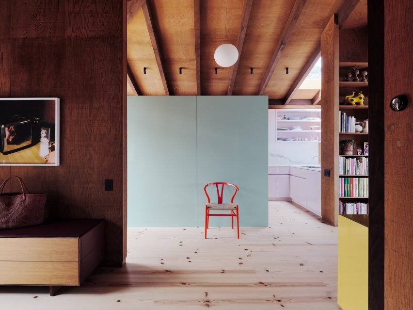 Image showcasing Redwood House with bright kitchen and mint green storage against timber-heavy interiors.