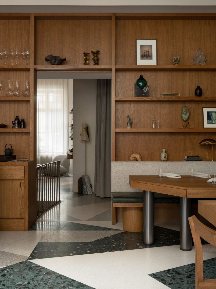 Wood-panelled wall and honey-tinted oak shelving filled with crockery and artwork.