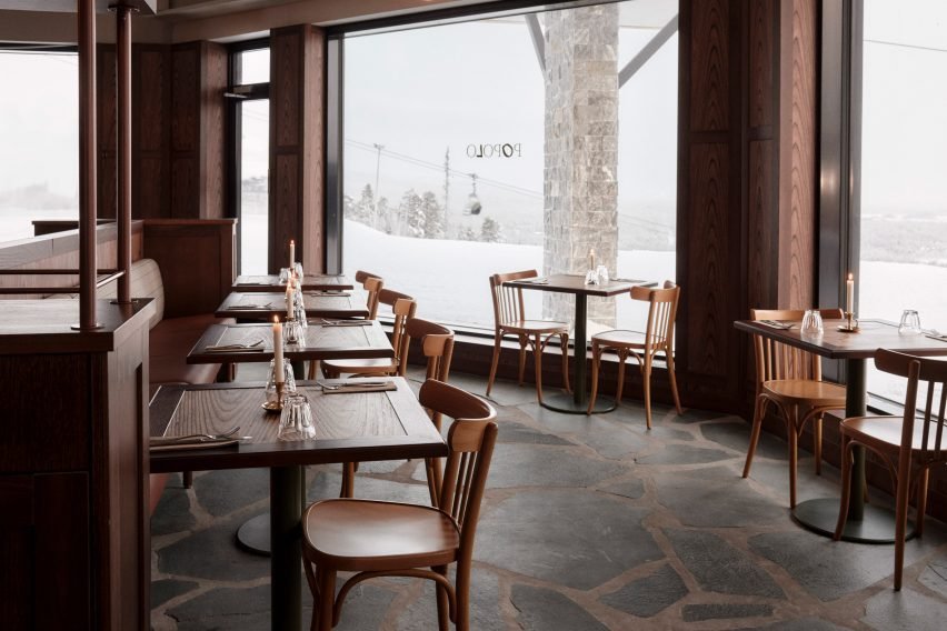 Dining tables overlook ski slopes, enhancing the atmosphere of the space.