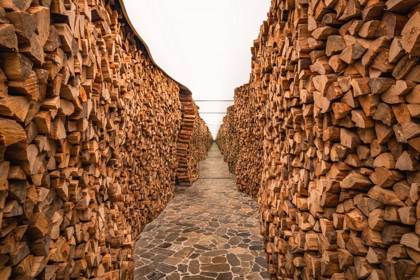 Entrance pathway lined with firewood, leading to the restaurant.