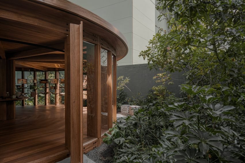 Visitors approach the space via an unassuming metal gateway, passing through a tunnel filled with potted plants before emerging into the courtyard.