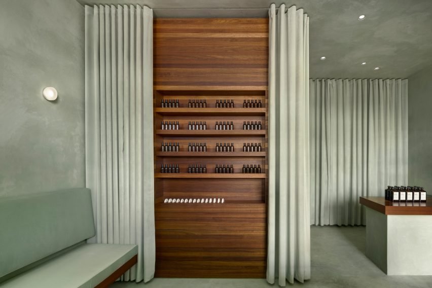 The mint-green curtains open to reveal more products displayed on reclaimed walnut shelves.