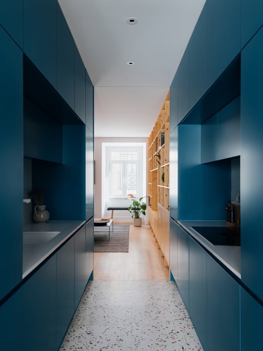 This photograph displays the kitchen, which features deep-blue cabinets contrasted with terrazzo flooring, showcasing a modern aesthetic.