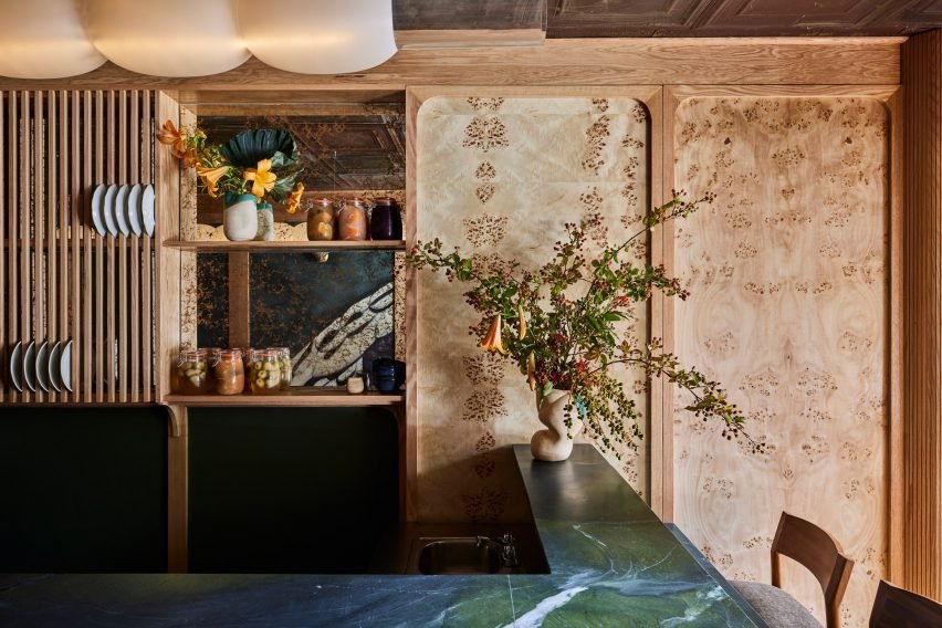 Interior shot showing blue-green Avocatus stone bar counter with decorations including ceramic vases and flowers.