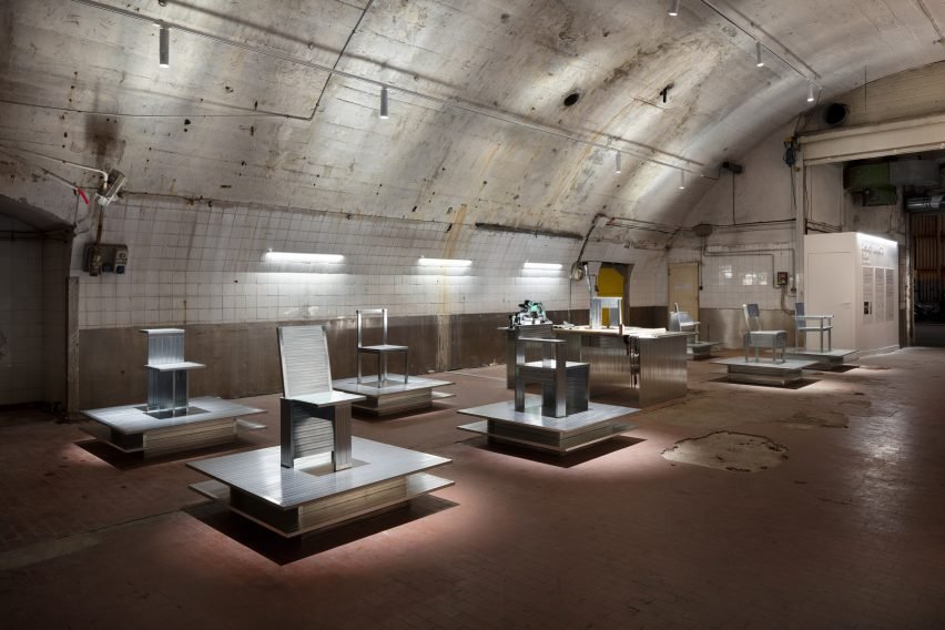 A series of steel chairs on podiums within a railway arch.