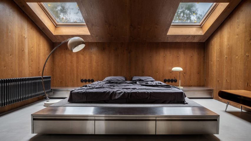 Bed in wood-panelled bedroom with retro lighting