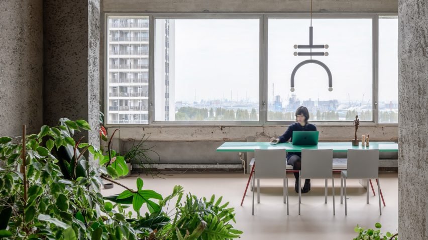 Dining area in Landaburu Borda, featuring a large wooden table with red chairs against concrete walls.