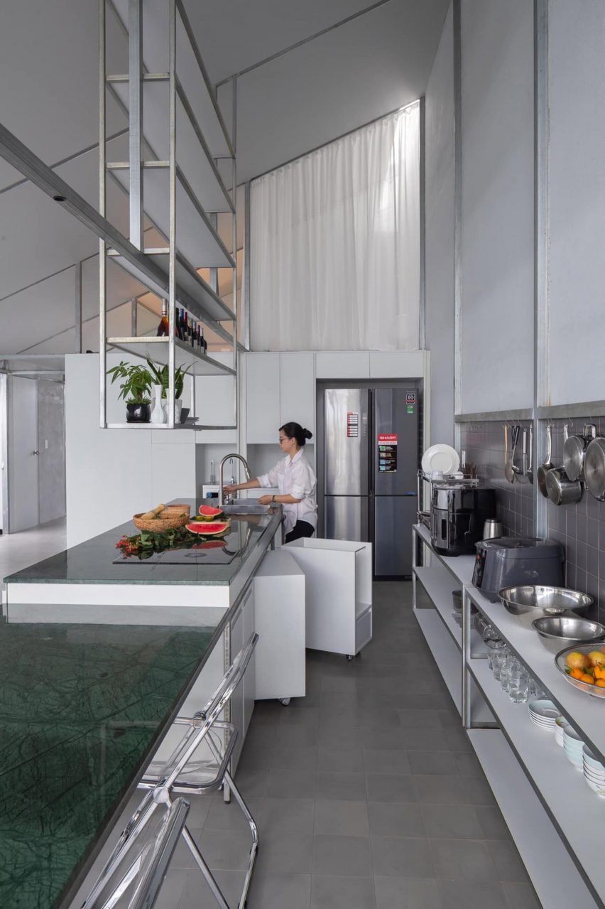 Image of the kitchen in Binh Thuan House, demonstrating an industrial feel with an exposed steel frame and simple white curtains.