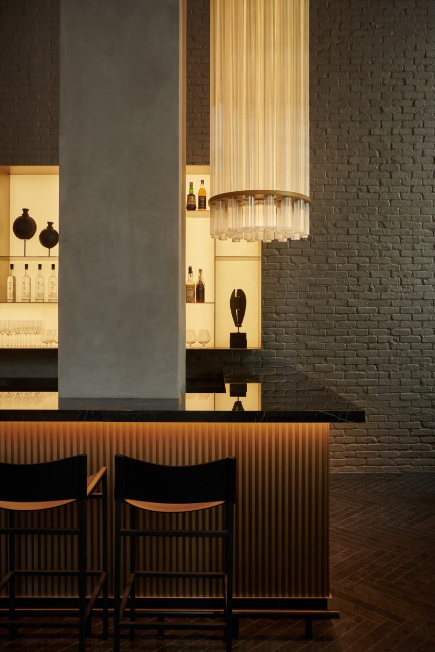 The bar area features a glossy black counter with fluted front and a dramatic light fixture.