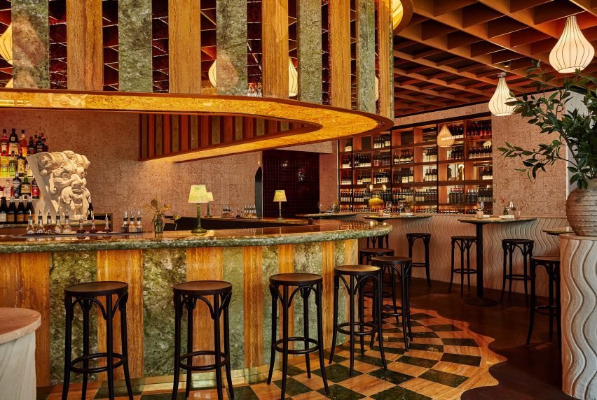 The organically shaped bar is clad in stripes of marble and glass.