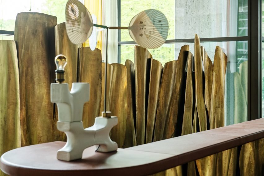 The hotel lobby featuring a brass reception desk and a lamp designed by Lionel Jadot.